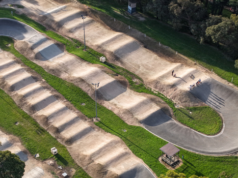 Melbourne Australia 22 September 2026 Aerial view of a BMX track featuring dirt mounds and banked curves surrounded by green grass and trees. Melbourne Australia 22 September 2026 Aerial view of a BMX track featuring dirt mounds and banked curves surrounded by green grass and trees.
