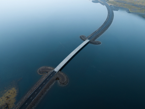 Aerial view of a road dramatically bisects the serene inky waters connecting distant shores under the vast Icelandic sky Westfjords Iceland. Aerial view of a road dramatically bisects the serene inky waters connecting distant shores under the vast Icelandic sky Westfjords Iceland.