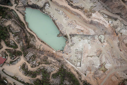 Aerial view of Cantera Porrino granite quarry showing turquoise water stacked stone blocks and industrial excavation patterns in O Porrino Pontevedra Spain. Aerial view of Cantera Porrino granite quarry showing turquoise water stacked stone blocks and industrial excavation patterns in O Porrino Pontevedra Spain.