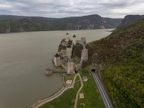 Aerial view of the historic Golubac Fortress on the Danube River featuring stone towers defensive walls and a nearby road tunnel in Golubac Branicevski Okrug Serbia. Aerial view of the historic Golubac Fortress on the Danube River featuring stone towers defensive walls and a nearby road tunnel in Golubac Branicevski Okrug Serbia.
