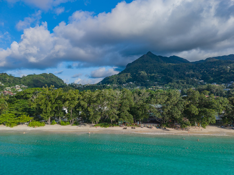 Aerial view of turquoise waters gently kissing the sandy shorelines framed by lush green trees against the backdrop of majestic mountains Victoria Seychelles. Aerial view of turquoise waters gently kissing the sandy shorelines framed by lush green trees against the backdrop of majestic mountains Victoria Seychelles.