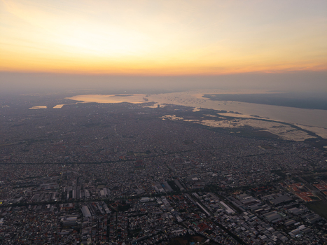 Aerial view of the historic Surabaya old town at sunset featuring dense urban rooftops industrial areas and the coastline in Surabaya East Java Indonesia.