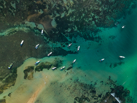 Aerial view of small boats scattered across shallow turquoise waters and coral reefs in Kecamatan Denpasar Selatan Bali Indonesia.