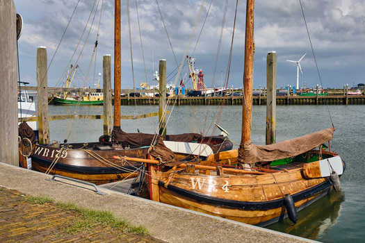 Den Oever Netherlands 18 May 2026 View of historic Wieringeraak sailing vessels docked in the fishing harbor with a wind turbine and cloudy sky in the background. Den Oever Netherlands 18 May 2026 View of historic Wieringeraak sailing vessels docked in the fishing harbor with a wind turbine and cloudy sky in the background.
