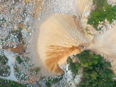 Aerial view of a mining site with heavy machinery extracting sand and soil from rocky terrain surrounded by lush vegetation in Bukit Tambun Penang Malaysia. Aerial view of a mining site with heavy machinery extracting sand and soil from rocky terrain surrounded by lush vegetation in Bukit Tambun Penang Malaysia.