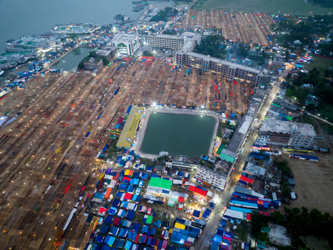 Aerial view of a sprawling landscape dotted with colorful tents and buildings converging around a serene pond Charmonai Barisal Division Bangladesh. Aerial view of a sprawling landscape dotted with colorful tents and buildings converging around a serene pond Charmonai Barisal Division Bangladesh.