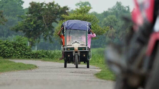 View of an auto rickshaw driving on a rural road in Bangladesh. View of an auto rickshaw driving on a rural road in Bangladesh.
