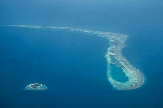 Aerial view of turquoise shallows embrace sandy strips in the vast deep blue ocean Flight from Male to Hanimaadhoo island Maldives.