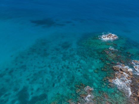 Aerial view of the turquoise sea meeting the rocky coast with a dance of light and shadow Vista do Mar Mahe island Seychelles. Aerial view of the turquoise sea meeting the rocky coast with a dance of light and shadow Vista do Mar Mahe island Seychelles.