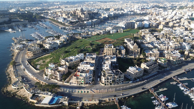 Aerial view of the coastal cityscape of Valletta featuring a marina with yachts historic stone buildings and green spaces along the waterfront in Valletta Port Region Malta. Aerial view of the coastal cityscape of Valletta featuring a marina with yachts historic stone buildings and green spaces along the waterfront in Valletta Port Region Malta.