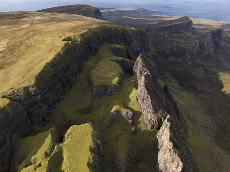Aerial view of the dramatic Quiraing landscape on the Isle of Skye featuring rugged cliffs grassy plateaus and rocky pinnacles in Scotland United Kingdom. Aerial view of the dramatic Quiraing landscape on the Isle of Skye featuring rugged cliffs grassy plateaus and rocky pinnacles in Scotland United Kingdom.