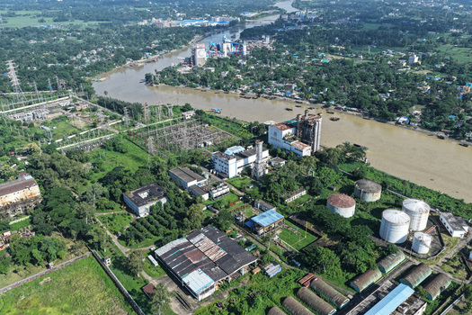 Aerial view of the industrial facility and power plant along the Karnaphuli River with storage tanks and surrounding lush greenery in Chattogram Chattogram Division Bangladesh.