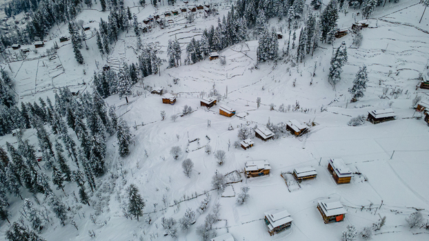 Aerial view of snow laden wooden cabins nestled amidst a pristine white landscape dotted with coniferous trees Sharda Azad Kashmir Pakistan. Aerial view of snow laden wooden cabins nestled amidst a pristine white landscape dotted with coniferous trees Sharda Azad Kashmir Pakistan.