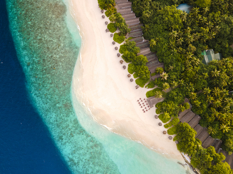 Aerial view of a white sand beach along the coastline at sunrise Baa Atoll Maldives.