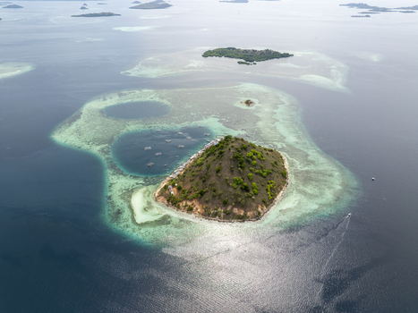 Aerial view of Pulau Kukusan island surrounded by turquoise coral reefs clear blue water and small boats in Komodo East Nusa Tenggara Indonesia. Aerial view of Pulau Kukusan island surrounded by turquoise coral reefs clear blue water and small boats in Komodo East Nusa Tenggara Indonesia.