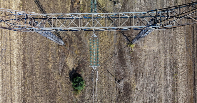 Aerial view of electric power transmission lines spanning across agricultural fields in Pancevo Serbia.