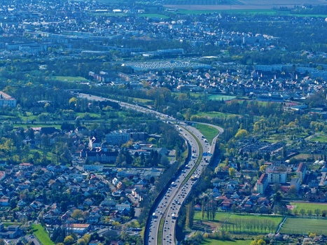 Aerial view of a highway cutting through the urban sprawl flanked by vibrant buildings and lush greenery Sausheim Grand Est France.