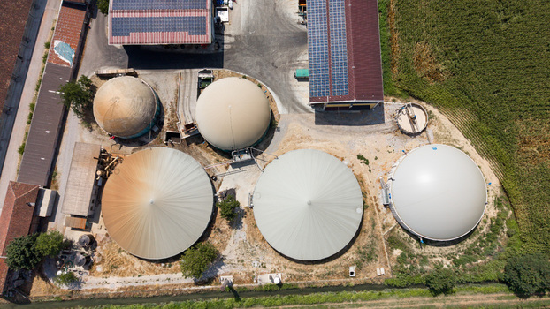 Aerial view of a biomethane production facility with large storage tanks and solar panels on agricultural buildings in Tavazzano con Villavesco Lombardy Italy.