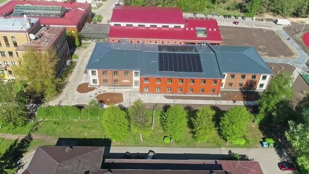 Aerial view of a brick building with solar panels in Latvia.