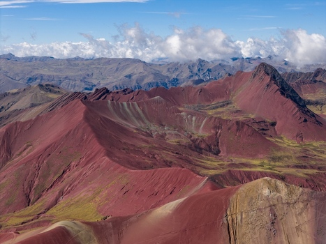 Aerial view of the colorful mineral rich slopes of Vinicunca Rainbow Mountain with rugged terrain and distant peaks under a blue sky in Cusco Cuzco Peru. Aerial view of the colorful mineral rich slopes of Vinicunca Rainbow Mountain with rugged terrain and distant peaks under a blue sky in Cusco Cuzco Peru.