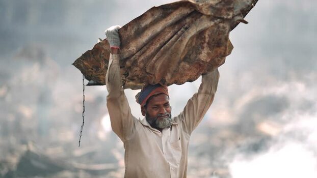View of a man carrying heavy scrap metal on his head Bangladesh. View of a man carrying heavy scrap metal on his head Bangladesh.