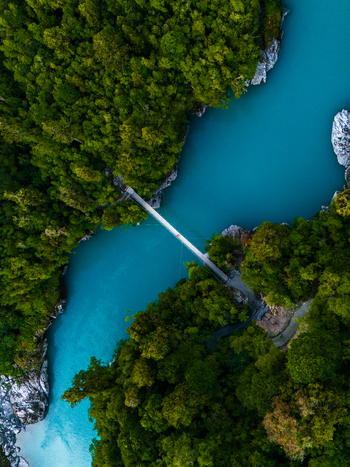 Aerial view of the Hokitika River s milky turquoise waters winding through a vibrant green gorge spanned by a narrow footbridge Hokitika Gorge West Coast Region New Zealand. Aerial view of the Hokitika River s milky turquoise waters winding through a vibrant green gorge spanned by a narrow footbridge Hokitika Gorge West Coast Region New Zealand.