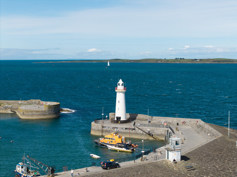 Aerial view of Donaghadee Harbour with its iconic white lighthouse stone pier moored boats and calm blue sea in Donaghadee Northern Ireland United Kingdom. Aerial view of Donaghadee Harbour with its iconic white lighthouse stone pier moored boats and calm blue sea in Donaghadee Northern Ireland United Kingdom.
