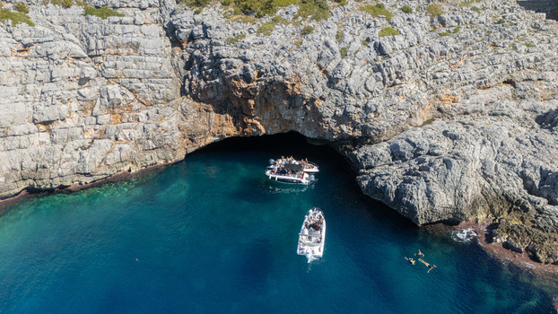 Aerial view of a sea cave with turquoise water motorboats and people swimming in Tivat Tivat Municipality Montenegro. Aerial view of a sea cave with turquoise water motorboats and people swimming in Tivat Tivat Municipality Montenegro.