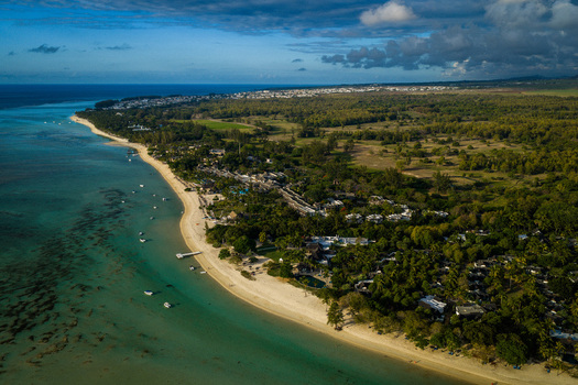 Aerial view of the Mauritius Island coastline featuring a pristine white sandy beach turquoise lagoon with small boats and lush tropical forests Moka District Mauritius. Aerial view of the Mauritius Island coastline featuring a pristine white sandy beach turquoise lagoon with small boats and lush tropical forests Moka District Mauritius.