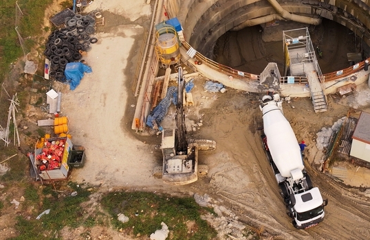 Aerial view of a construction site featuring a large circular shaft a concrete mixer truck and an excavator on the dirt ground in Avcilar Istanbul Turkiye. Aerial view of a construction site featuring a large circular shaft a concrete mixer truck and an excavator on the dirt ground in Avcilar Istanbul Turkiye.
