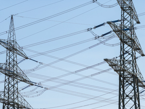 Aerial view of Amprion Umspannwerk high voltage transmission towers with intricate power lines against a clear blue sky in Pfungstadt Hessen Germany.