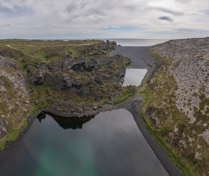 Aerial view of Djupalonssandur with its black pebble beach volcanic rock formations and calm pools of water in Iceland. Aerial view of Djupalonssandur with its black pebble beach volcanic rock formations and calm pools of water in Iceland.