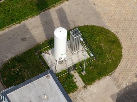 Aerial view of an industrial gas tank and heat exchanger unit on a concrete pad surrounded by grass and paved pathways in Warsaw Mazowieckie Poland. Aerial view of an industrial gas tank and heat exchanger unit on a concrete pad surrounded by grass and paved pathways in Warsaw Mazowieckie Poland.