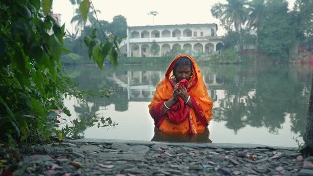 View of a woman performing a ritual in a pond in Bogura Bangladesh. View of a woman performing a ritual in a pond in Bogura Bangladesh.