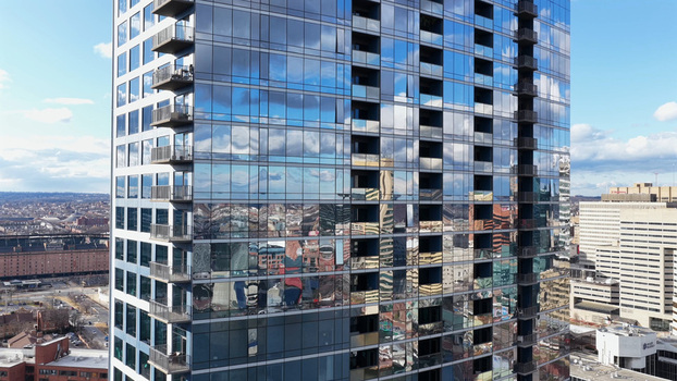 Aerial view of a modern glass high rise building reflecting the sky and surrounding urban landscape in the Inner Harbor area of Baltimore Maryland United States.