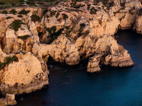 Aerial view of Ponta da Piedade featuring dramatic golden limestone cliffs sea caves and turquoise waters along the Algarve coastline in Lagos Faro Portugal.