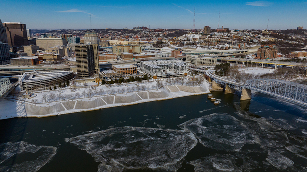 Aerial view of the snow covered riverfront with ice floes on the water and the city skyline under a clear blue sky in Cincinnati Ohio United States. Aerial view of the snow covered riverfront with ice floes on the water and the city skyline under a clear blue sky in Cincinnati Ohio United States.