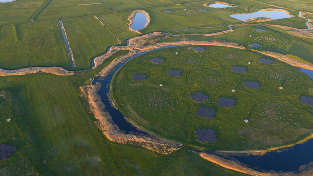 Aerial view of the LOFAR superterp radio telescope station with its circular island and antenna arrays surrounded by lush green fields and water channels Buinen Drenthe Netherlands. Aerial view of the LOFAR superterp radio telescope station with its circular island and antenna arrays surrounded by lush green fields and water channels Buinen Drenthe Netherlands.