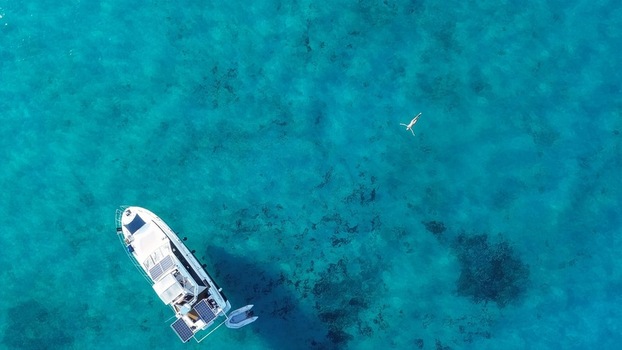 Aerial view of Blue Lagoon with a boat and a person swimming in clear turquoise water Malta.