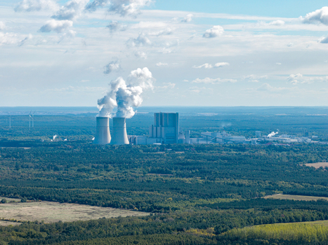 Aerial view of the Schwarze Pumpe power station with its cooling towers emitting steam surrounded by vast forests and open landscape in Spremberg Brandenburg Germany. Aerial view of the Schwarze Pumpe power station with its cooling towers emitting steam surrounded by vast forests and open landscape in Spremberg Brandenburg Germany.