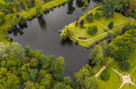 Aerial view of the park in Pelplin featuring a calm pond lush green trees manicured lawns and winding pathways in Pelplin Pomeranian Voivodeship Poland. Aerial view of the park in Pelplin featuring a calm pond lush green trees manicured lawns and winding pathways in Pelplin Pomeranian Voivodeship Poland.