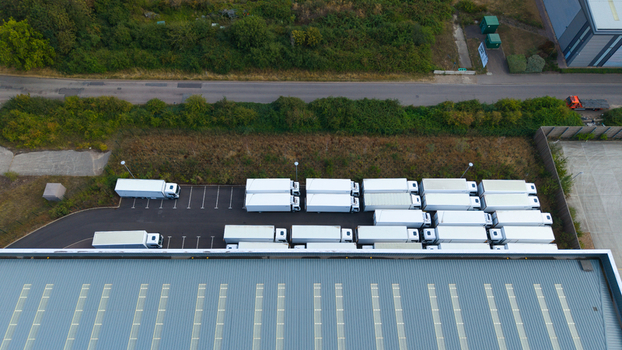 Aerial view of a logistics hub with rows of white semi trailers parked beside a large industrial warehouse in Bedford England United Kingdom. Aerial view of a logistics hub with rows of white semi trailers parked beside a large industrial warehouse in Bedford England United Kingdom.