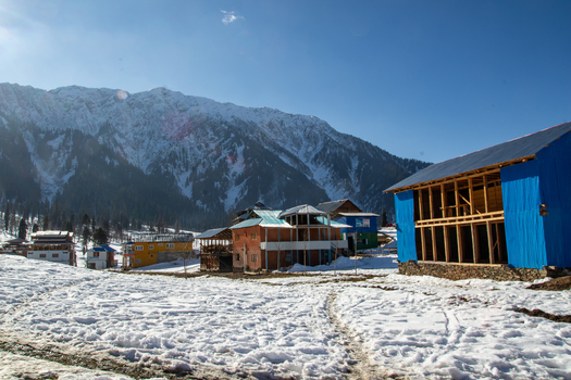 View of Arang Kel village with wooden houses and structures set against snow covered mountains under a clear blue sky in Arang Kel Kashmir Pakistan. View of Arang Kel village with wooden houses and structures set against snow covered mountains under a clear blue sky in Arang Kel Kashmir Pakistan.