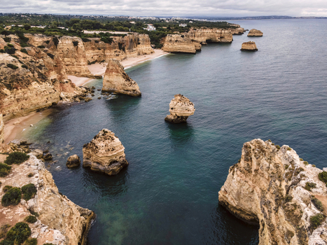 Aerial view of Praia da Marinha and Praia da Mesquita with natural arch at sunrise along the coastline in Lagoa Faro Algarve region Portugal.