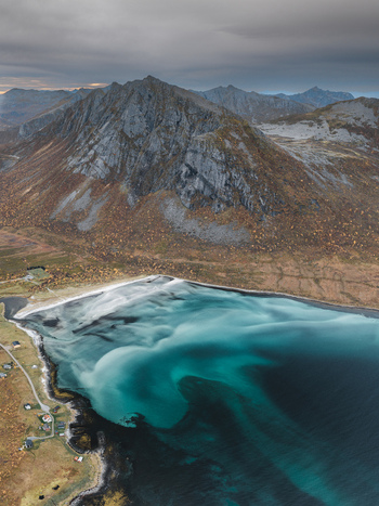 Aerial view of the dramatic mountains and turquoise waters of the bay in Senja Troms Norway.