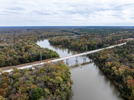 Aerial view of a bridge cutting through the autumnal trees and reflecting the sky in the waters below Fort Motte South Carolina United States.
