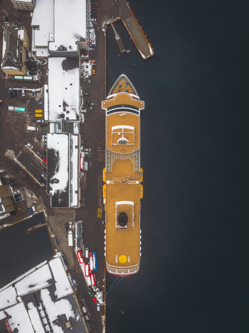 Aerial view of a cruise ship docked at the snowy harbor contrasting with the dark tranquil waters of Svolv&aelig;r Nordland Norway.