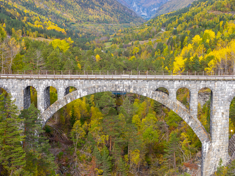 Aerial view of the historic Kylling Bridge spanning a lush valley with vibrant autumn foliage and dense pine forests in Verma More og Romsdal Norway. Aerial view of the historic Kylling Bridge spanning a lush valley with vibrant autumn foliage and dense pine forests in Verma More og Romsdal Norway.