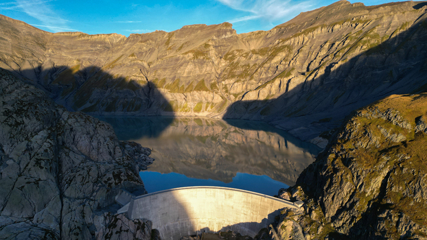 Aerial view of the Vieux Emosson dam and lake surrounded by rugged mountain peaks and rocky slopes under a clear blue sky in Finhaut Valais Switzerland. Aerial view of the Vieux Emosson dam and lake surrounded by rugged mountain peaks and rocky slopes under a clear blue sky in Finhaut Valais Switzerland.