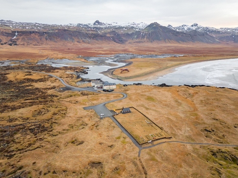 Aerial view of the iconic black church of Budir in a vast rugged landscape with snow capped mountains a winding road and the coastline of Budir Snaefellsbaer Iceland. Aerial view of the iconic black church of Budir in a vast rugged landscape with snow capped mountains a winding road and the coastline of Budir Snaefellsbaer Iceland.
